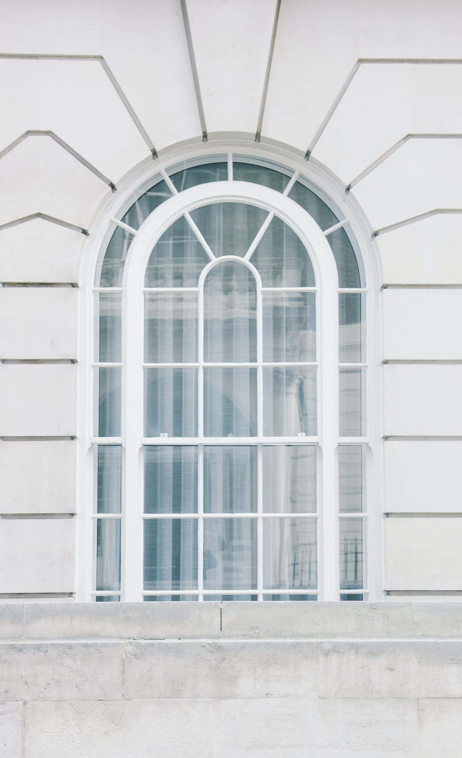 arch-shaped white sliding window having grill