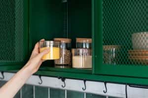 Woman Kitchen Taking Jar Out Of Cabinet 